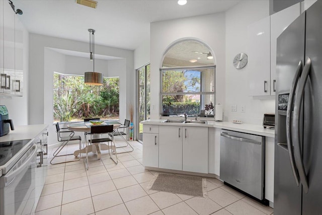 kitchen with light tile patterned floors, appliances with stainless steel finishes, white cabinets, and hanging light fixtures