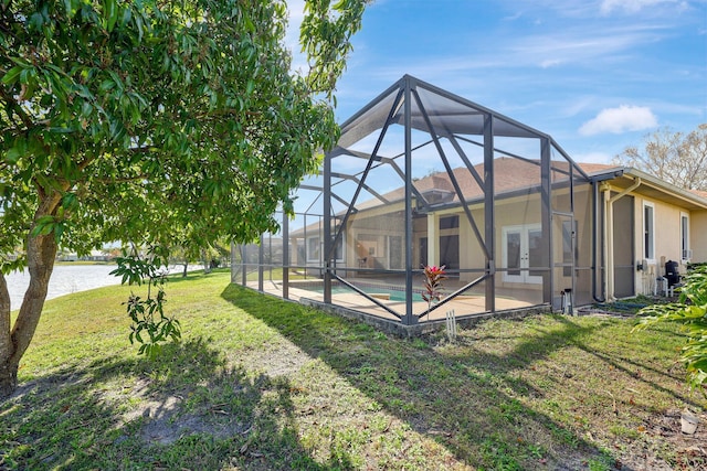 view of yard featuring a lanai, a patio area, french doors, and a water view