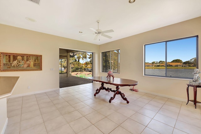 tiled dining space featuring a wealth of natural light, ceiling fan, and a water view