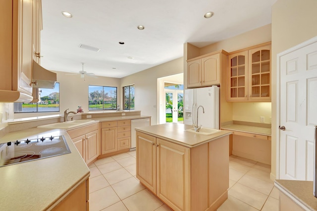 kitchen featuring a kitchen island with sink, sink, white appliances, and light brown cabinets