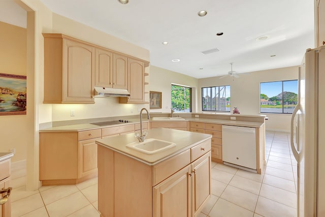 kitchen featuring a kitchen island with sink, sink, white appliances, and light brown cabinets