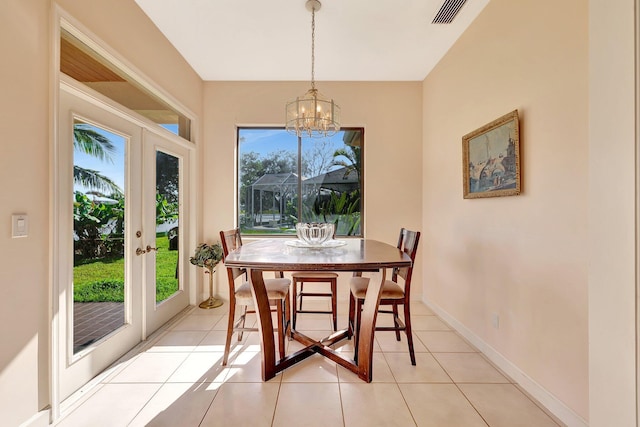 tiled dining space with an inviting chandelier and french doors