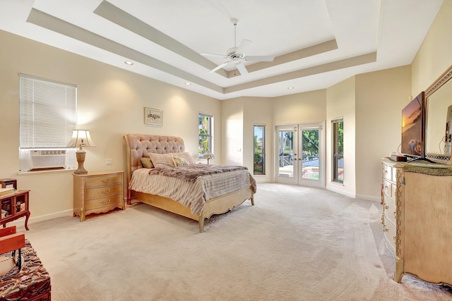 bedroom featuring light colored carpet, access to exterior, ceiling fan, a tray ceiling, and french doors