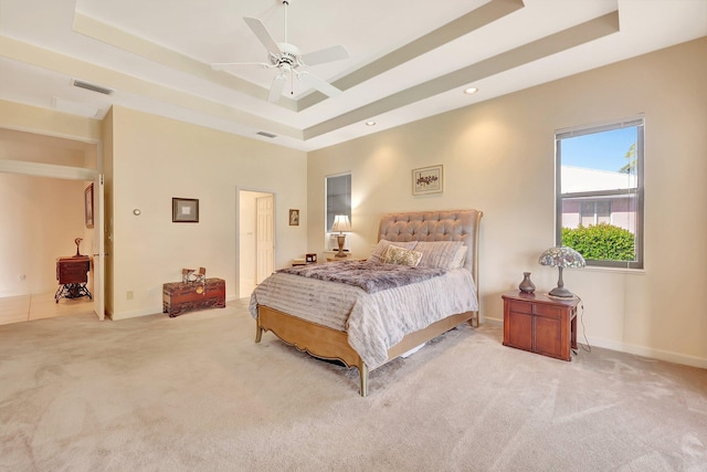 bedroom with ceiling fan, a tray ceiling, and light carpet