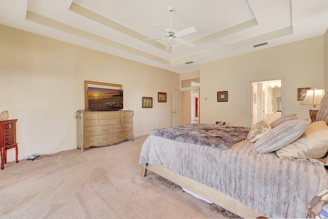 carpeted bedroom with ceiling fan and a tray ceiling