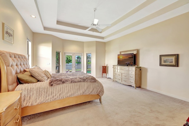 bedroom with french doors, light carpet, access to outside, a tray ceiling, and ceiling fan