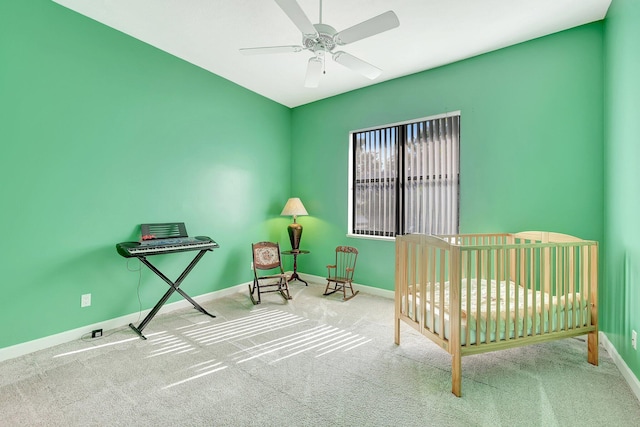 unfurnished bedroom with a nursery area, carpet flooring, and ceiling fan