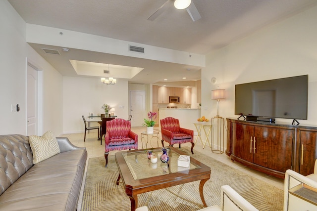 living room with ceiling fan with notable chandelier and a raised ceiling