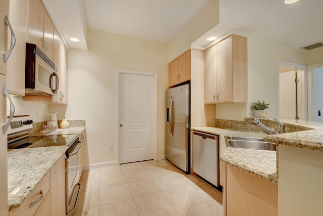 kitchen with light tile patterned floors, appliances with stainless steel finishes, light brown cabinets, light stone counters, and sink