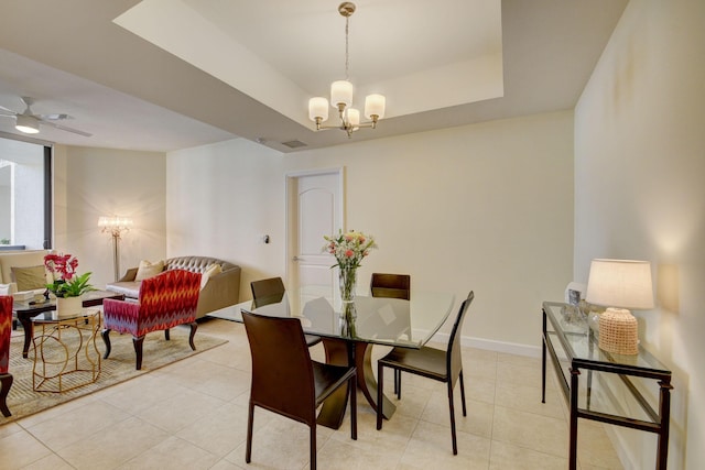 dining area featuring ceiling fan with notable chandelier, a raised ceiling, and light tile patterned flooring