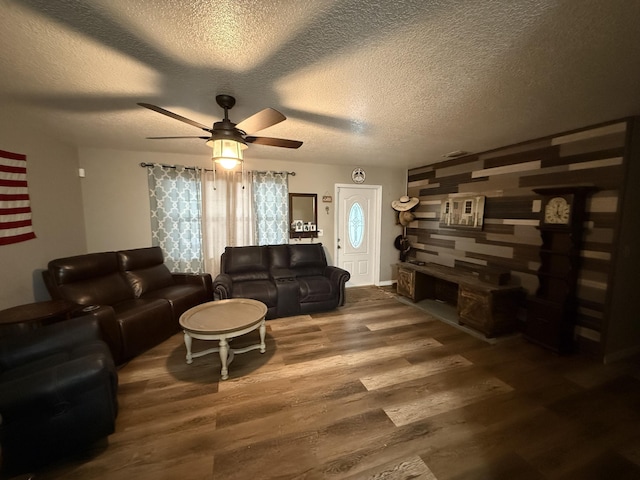 living room featuring ceiling fan, dark wood-type flooring, and a textured ceiling