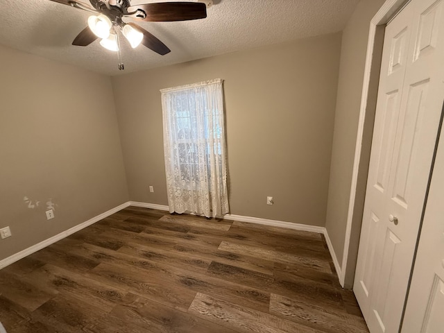 empty room featuring a textured ceiling, ceiling fan, and dark hardwood / wood-style floors