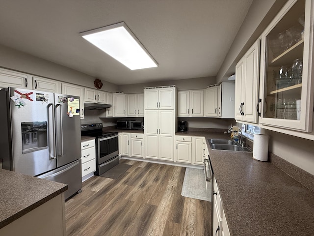 kitchen with dark wood-type flooring, appliances with stainless steel finishes, white cabinets, and sink