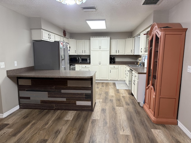 kitchen featuring white cabinets, kitchen peninsula, stainless steel appliances, and a textured ceiling