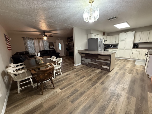 kitchen with decorative light fixtures, stainless steel fridge with ice dispenser, a textured ceiling, white cabinets, and ceiling fan with notable chandelier