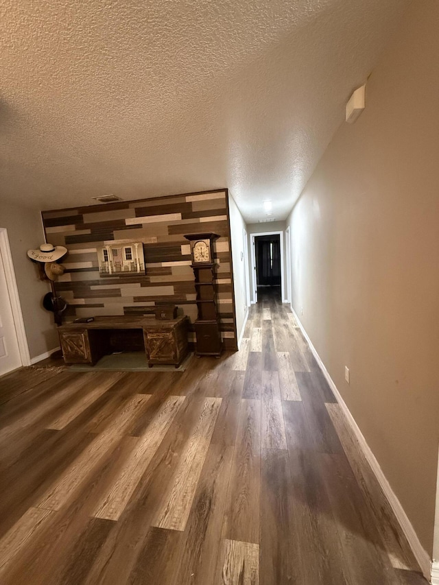 hall with a textured ceiling and dark hardwood / wood-style floors