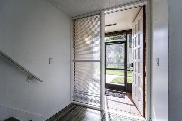 entryway with dark wood-type flooring, a textured ceiling, and a wall of windows