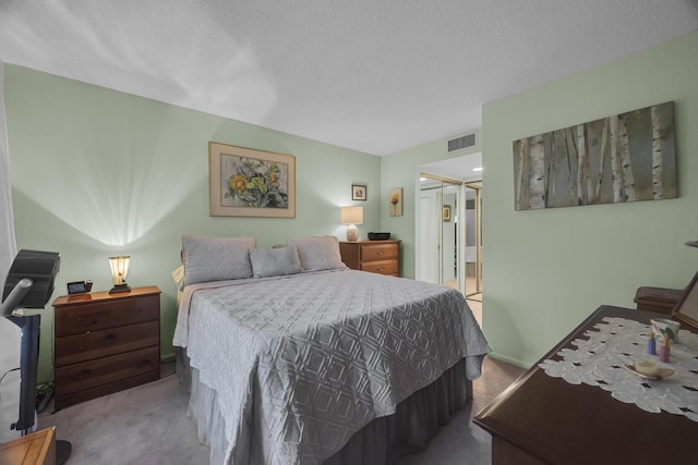 bedroom featuring a textured ceiling, ensuite bathroom, a closet, and light carpet