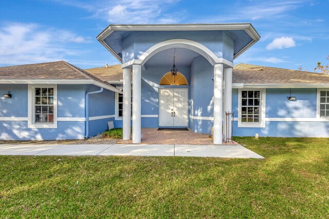 12855 87th St N, West Palm Beach, FL 33412 - doorway to property with stucco siding, roof with shingles, and a yard