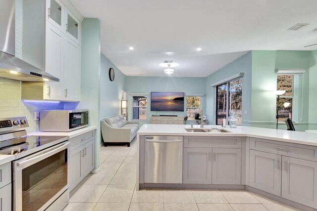 12855 87th St N, West Palm Beach, FL 33412 - kitchen with appliances with stainless steel finishes, wall chimney exhaust hood, open floor plan, tasteful backsplash, and a sink