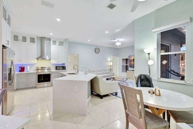 kitchen featuring sink, appliances with stainless steel finishes, white cabinetry, light tile patterned flooring, and wall chimney exhaust hood