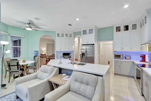 kitchen with sink, light tile patterned floors, a kitchen island with sink, backsplash, and stainless steel appliances