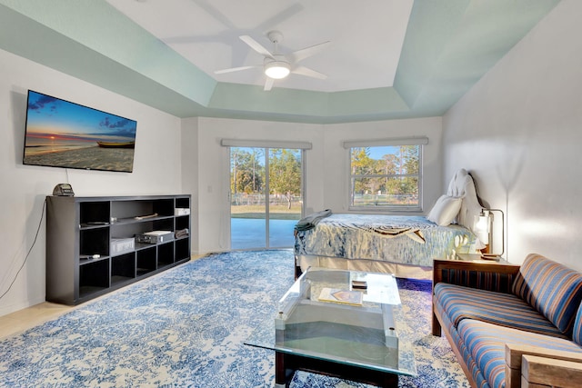 bedroom featuring access to exterior, ceiling fan, and a tray ceiling