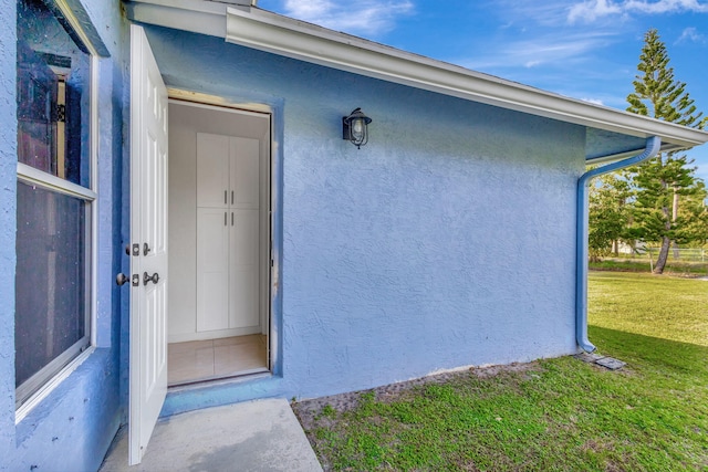 view of exterior entry with a lawn