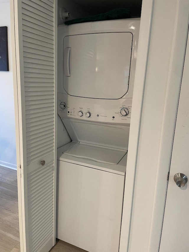 washroom with stacked washer / drying machine and light wood-type flooring