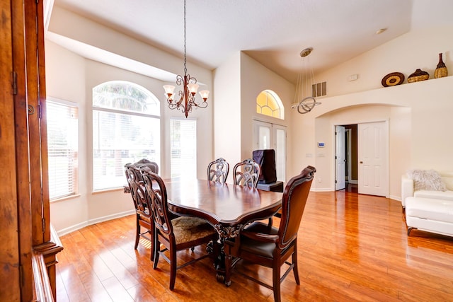 dining space featuring a notable chandelier, high vaulted ceiling, and light hardwood / wood-style flooring