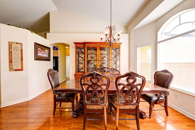 dining area with lofted ceiling, hardwood / wood-style floors, and an inviting chandelier