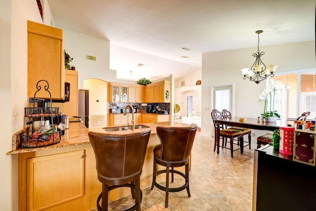 kitchen featuring sink, vaulted ceiling, light brown cabinets, kitchen peninsula, and backsplash