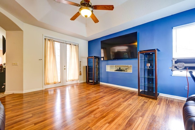 unfurnished living room featuring a tray ceiling, light hardwood / wood-style flooring, and ceiling fan