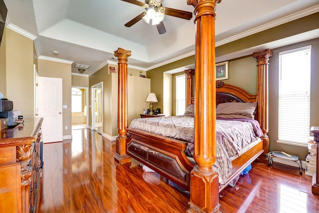 bedroom with decorative columns, hardwood / wood-style floors, and a tray ceiling