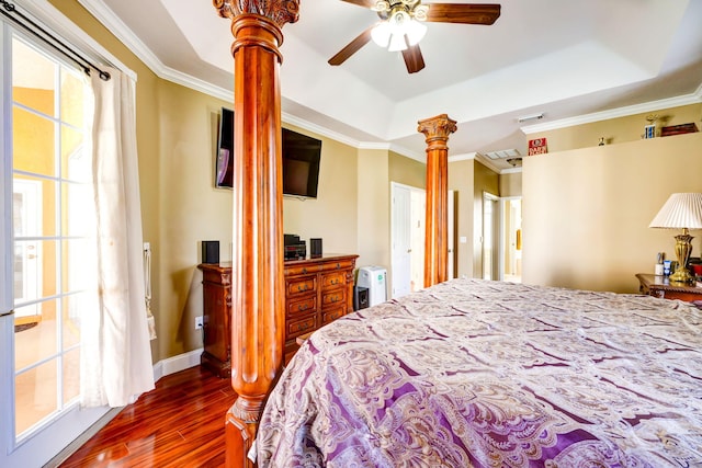 bedroom featuring crown molding, wood-type flooring, a tray ceiling, and ornate columns