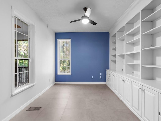 empty room featuring ceiling fan, a wealth of natural light, and a textured ceiling