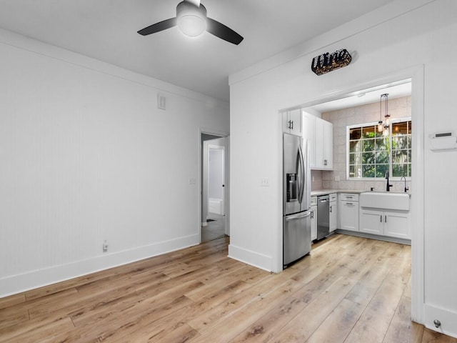 kitchen featuring white cabinetry, stainless steel appliances, backsplash, light wood-type flooring, and sink