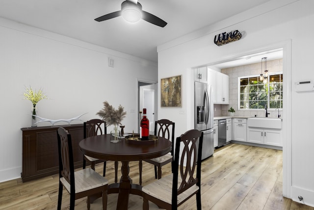 dining space with ceiling fan, sink, crown molding, and light wood-type flooring