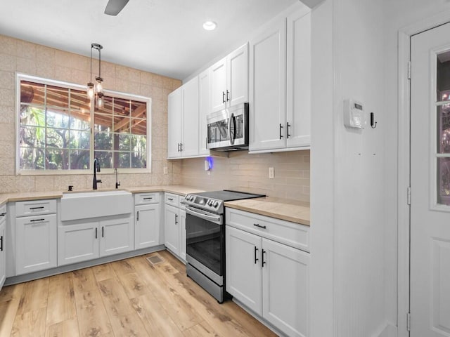 kitchen featuring white cabinetry, light hardwood / wood-style floors, stainless steel appliances, backsplash, and sink