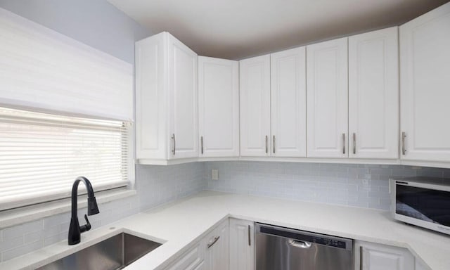 kitchen with white cabinets, decorative backsplash, appliances with stainless steel finishes, and sink