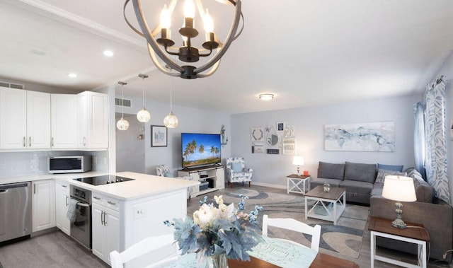 kitchen featuring backsplash, white cabinetry, appliances with stainless steel finishes, and an inviting chandelier