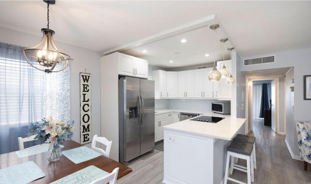 kitchen with decorative light fixtures, white cabinetry, appliances with stainless steel finishes, and a center island