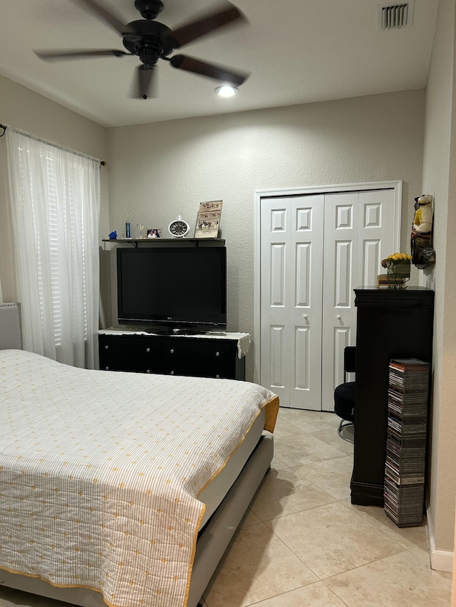 bedroom featuring ceiling fan, light tile patterned floors, and a closet