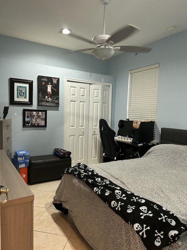 bedroom with ceiling fan, light tile patterned floors, and a closet