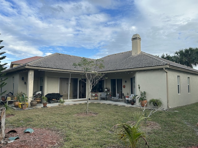 rear view of house featuring a lawn and a patio