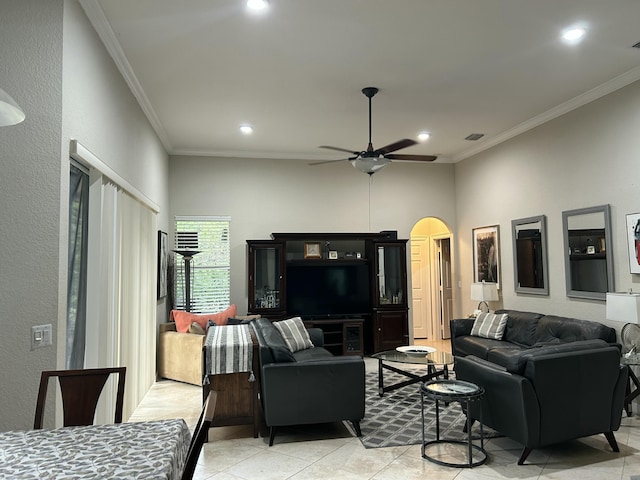 tiled living room featuring ceiling fan, a high ceiling, and crown molding