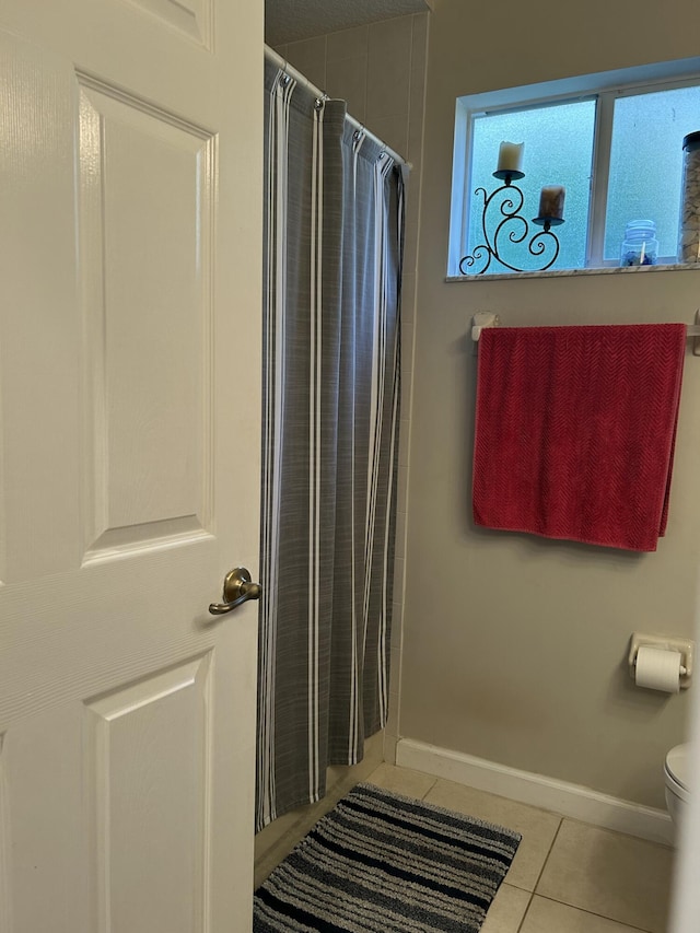 bathroom with toilet, tile patterned flooring, and curtained shower