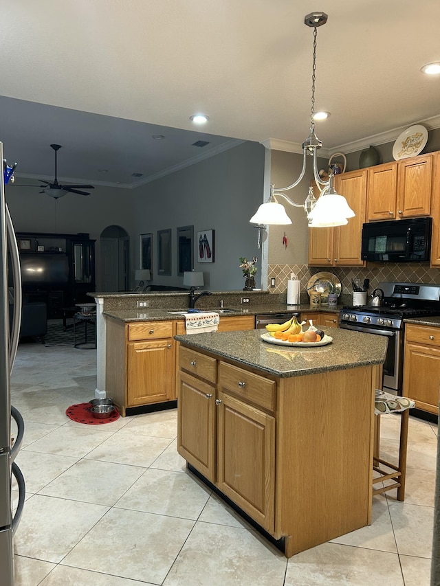 kitchen with ceiling fan, backsplash, appliances with stainless steel finishes, and a kitchen island