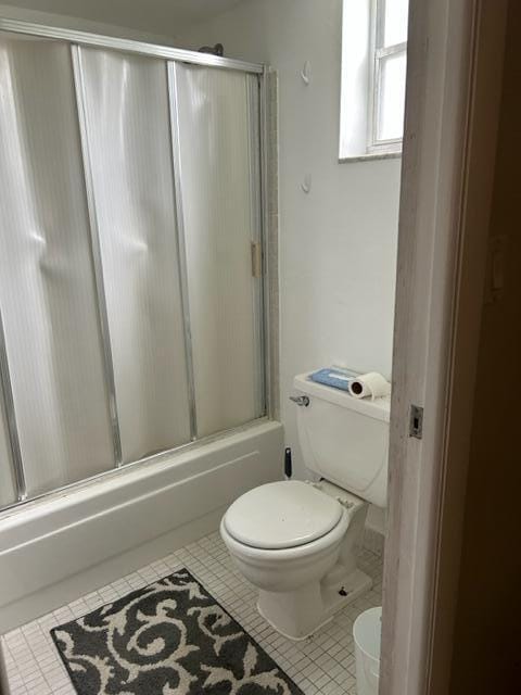 bathroom featuring toilet, tile patterned floors, and shower / bath combination with glass door