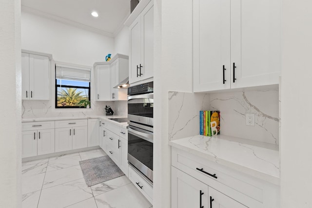 kitchen with light stone counters, ornamental molding, backsplash, and white cabinets